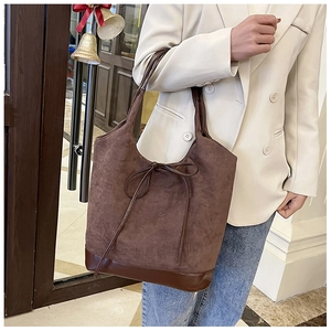 Brown faux suede tote bag with leather bottom and tie detail worn by a model in a beige suit