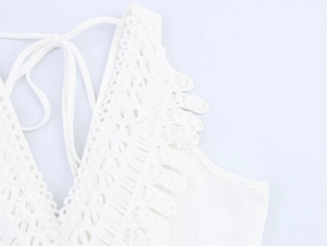 Detail of white vacation dress featuring crochet V-neckline and lace-up back straps