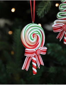 Detail of a red, white and green spiral candy cane ornament with a bow on Christmas tree