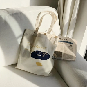Artistic canvas tote bag with color block patterns on a white sofa in natural light