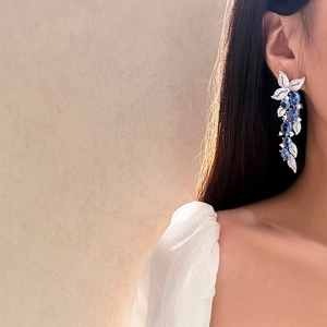 Close-up of sparkling blue zircon leaf tassel earrings worn on a female model