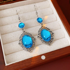 Detailed macro view of vintage silver earrings with blue stones in a beige velvet jewelry box
