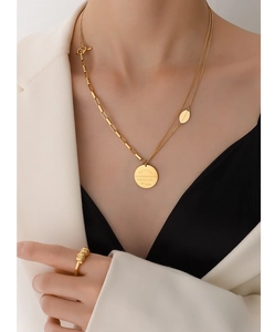 Detail of 18K gold double layer necklace with engraved letter pendant and twist ring
