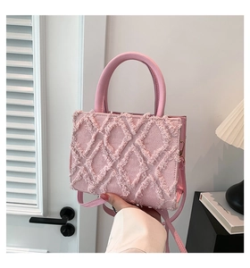 Detail of pink denim tote bag featuring fringed diamond pattern and adjustable shoulder strap