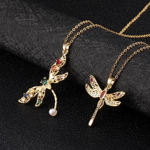 Macro detail of gold-plated dragonfly necklaces with multicolored zircon and pearl