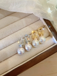 Close-up of gold and silver horseshoe-shaped earrings with pearls on beige velvet tray