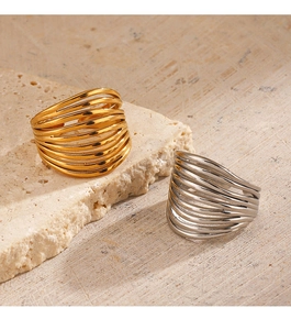 Detail of gold and silver minimalist multi-layer intertwined open rings on stone base