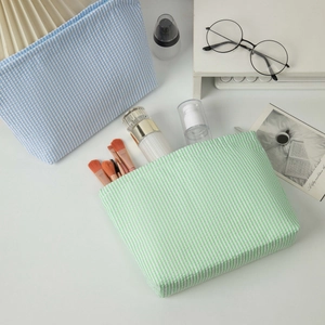 Macro shot of striped seersucker toiletry bags holding brushes and skincare products