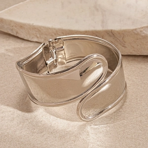 Close-up of polished silver wide cuff bracelet with asymmetric overlapping design
