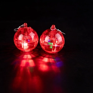 Detail of red disco ball earrings with internal lights reflecting on a dark surface