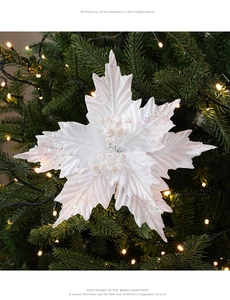White velvet Christmas flower with sequins and glitter on a lit Christmas tree