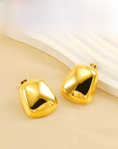 Dettaglio di orecchini geometrici placcati in oro 18K su tessuto con texture fine