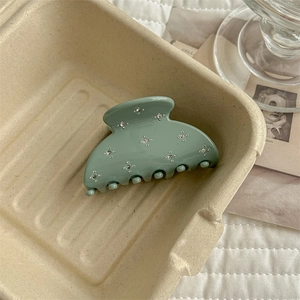 Detailed view of sage green crescent hair claw clip with sparkling star rhinestones