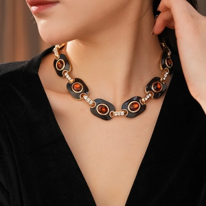 Detailed view of a vintage enamel necklace with orange gems and crystals on a model
