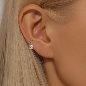 Macro view of gold s925 silver stud earring with clear square zircon on ear