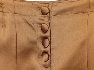 Detail view of four satin covered buttons on a bronze high-waist wide leg trouser