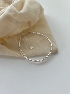 Detail of S925 silver beaded bracelet with white pearls and extender on linen pouch