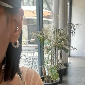 Close-up of S925 sterling silver star stud and textured hoop earrings on model