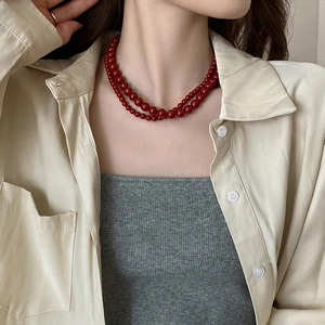 Collier double rang en perles de verre rouges porté sur le cou d'un mannequin