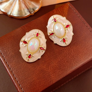 Macro shot of vintage round studs with cream enamel, red stones and iridescent gems