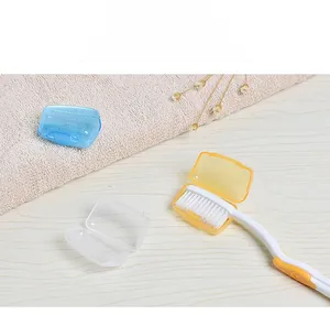 Portable plastic toothbrush head covers in blue, orange, and clear colors on a wooden table