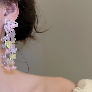Primer plano de elegantes pendientes colgantes de flores de cuentas pastel en una modelo