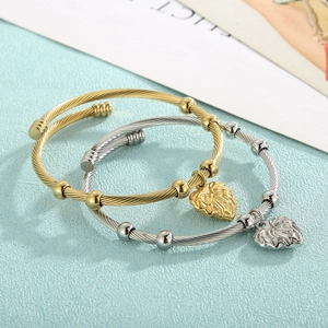 Close-up of twisted wire cable bracelets with leaf-shaped pendants in gold and silver