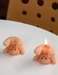 Macro detail of cute bear aromatherapy candle with warm flame on a white tabletop