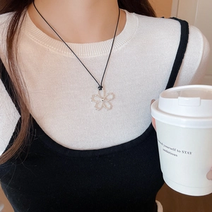 Gros plan d'un collier pendentif fleur avec cristaux porté par un mannequin dans un cadre chic