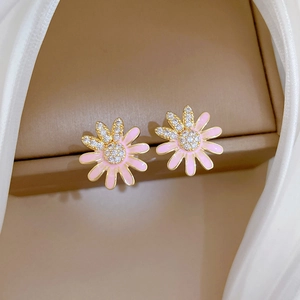 Detailed macro of daisy stud earrings with pink enamel petals and sparkling zircon center