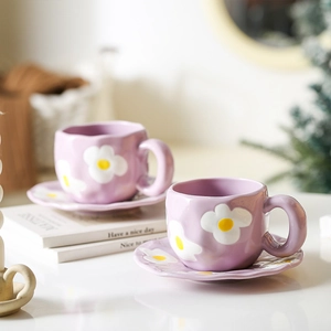 Detailed view of two purple ceramic coffee cups and saucers with white floral patterns