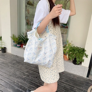 Close-up of white canvas tote with blue floral bear print and somakka beauté label