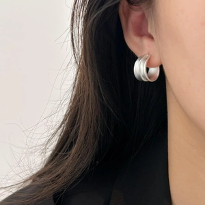 Macro shot of silver matte wide hoop earrings with textured brushed finish and wave design
