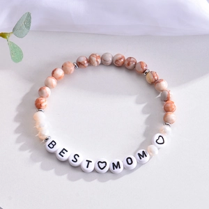 Detail of beaded bracelet with red marble stones and white BEST MOM letter beads