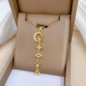 Detailed view of gold tassel necklace with star and moon charms in a jewelry box