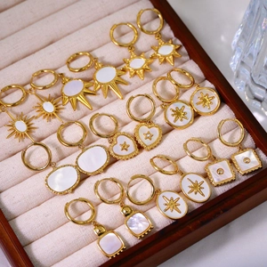 Detail of vintage gold earrings set with white shell inlays in celestial and geometric shapes