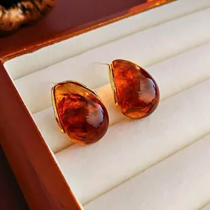 Macro view of vintage tiger eye geometric earrings with polished gold trim on velvet