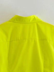 Détail macro du col de chemise jaune fluorescent et des coutures d'épaule sur tissu lisse