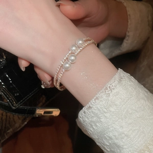 Détail macro d'un bracelet double couche en or rose avec perles et cristaux au poignet
