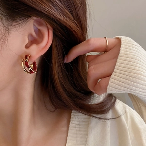 Close-up of model wearing C-shaped gold hoop earrings with burgundy velvet chain detail