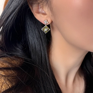 Close-up of model wearing vintage silver flower earrings with green gems and white pearls