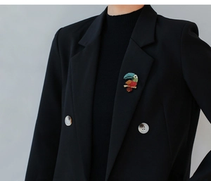 Detailed close-up of a colorful crystal parrot brooch pinned on a black suit jacket