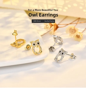 Macro view of gold and silver owl earrings featuring AAA cubic zirconia on ceramic