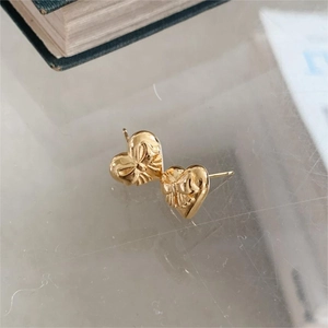 Close-up of golden 925 silver heart stud earrings with detailed bow relief texture