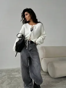 Gilet en maille blanc à nœuds avec un jean large gris pour un style décontracté