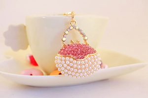 Detail of pink rhinestone and white pearl handbag keychain in golden finish