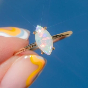 Detail of gold S925 silver ring featuring marquise-cut opal with vibrant fire and glow