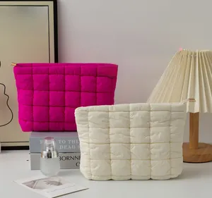 Close-up of quilted nylon pouches in magenta and cream white with zipper details
