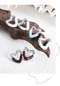 Detailed view of three heart earrings in white, blue and brown enamel on wood