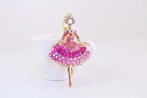 Close-up of pink rhinestone ballet girl keychain hanging on a white ceramic cup